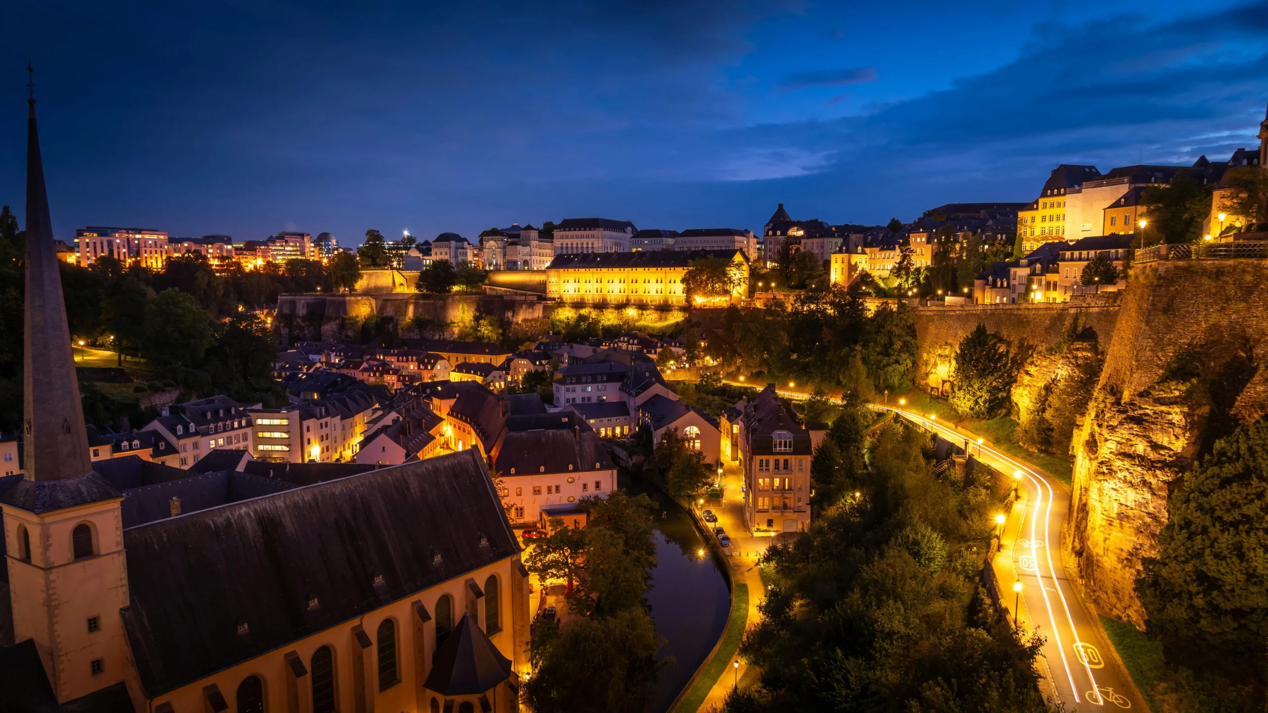 Night view of Luxembourg City with illuminated historic buildings, narrow streets, and the Grund district.