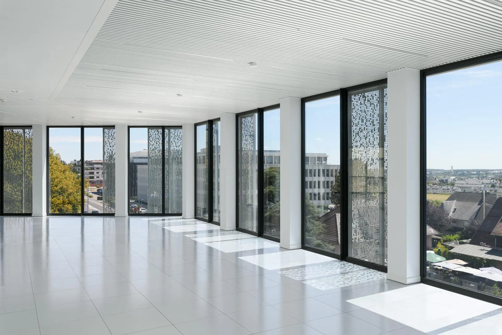 Bright empty office space with large floor-to-ceiling windows and modern design.